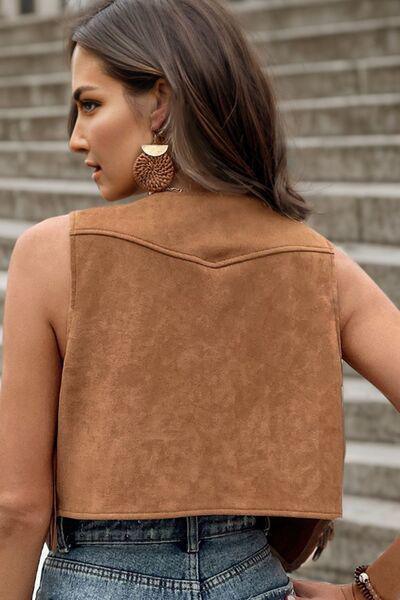 a woman wearing a tan leather vest and jeans