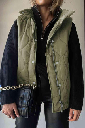 a woman wearing a green quilted vest and black pants
