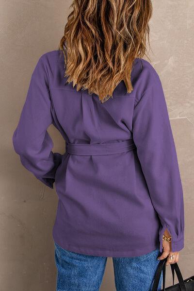 a woman in a purple shirt is holding a black bag