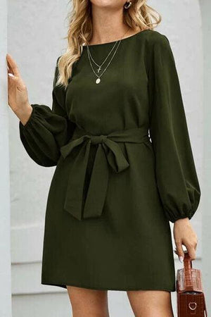 a woman in a green dress with a brown purse