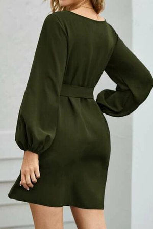 a woman wearing a green dress with long sleeves