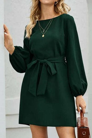 a woman in a green dress with a brown purse