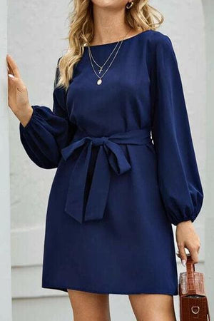 a woman in a blue dress with a brown purse