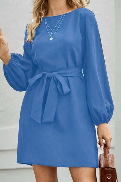 a woman in a blue dress holding a brown purse