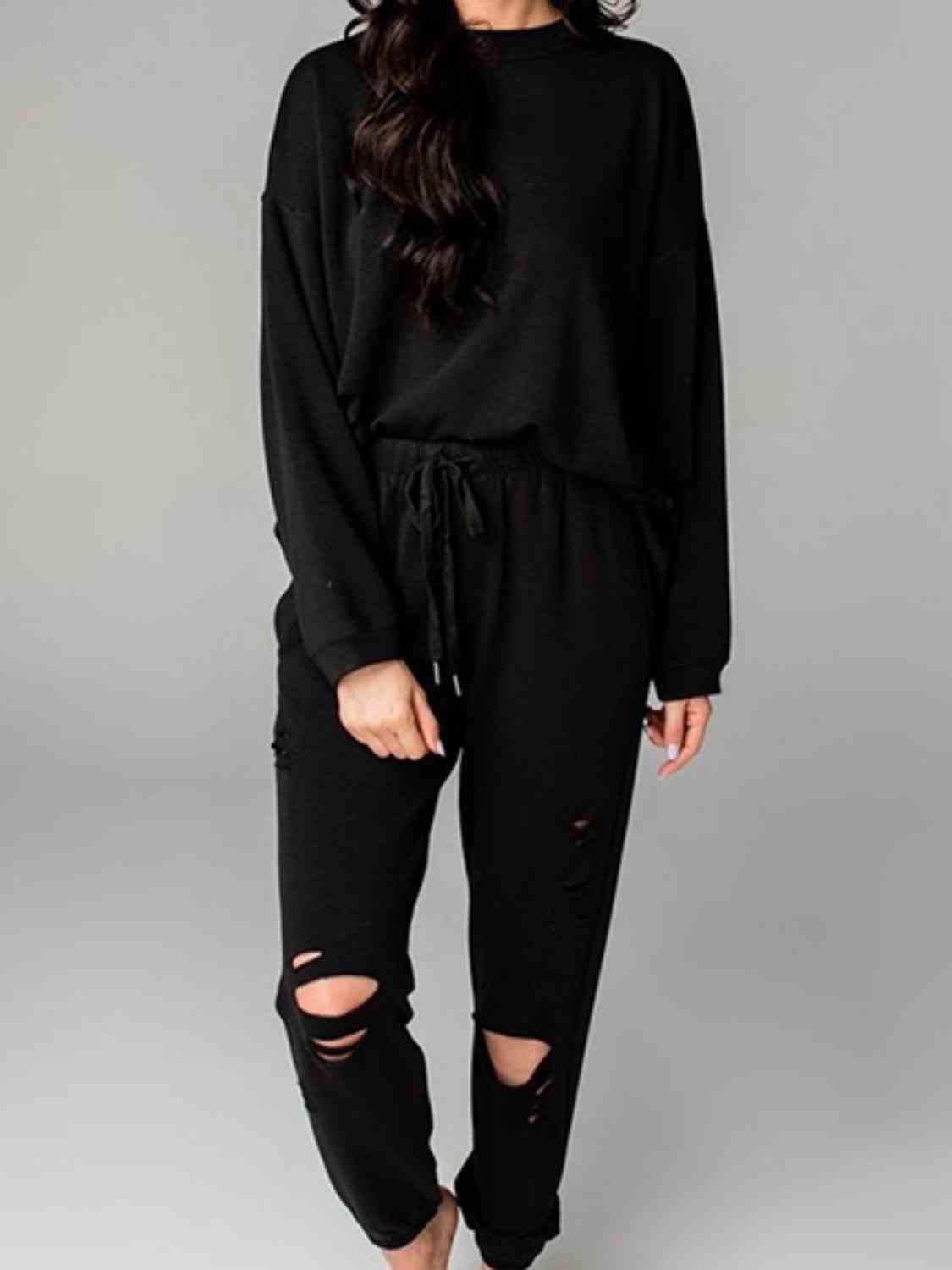 a woman wearing a black sweatshirt and ripped jeans