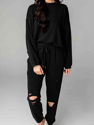 a woman wearing a black sweatshirt and ripped jeans