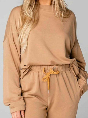 a woman wearing a tan sweatshirt and pants