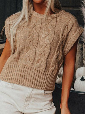 a woman wearing a tan sweater and white pants
