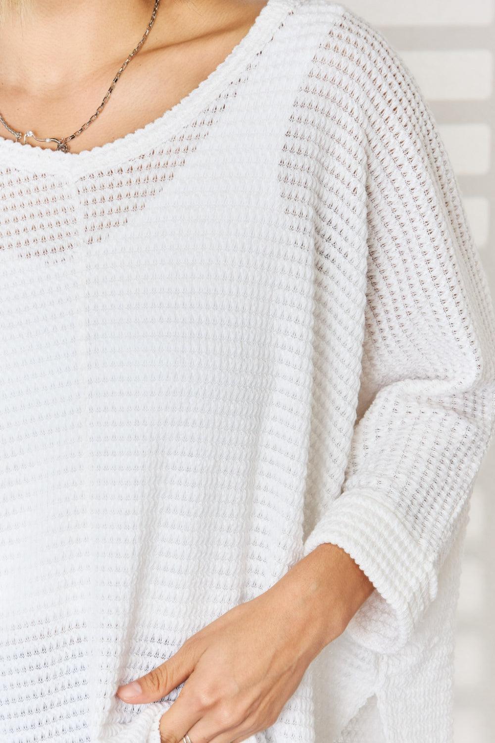 a woman wearing a white sweater and a necklace