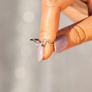 a woman's hand holding a ring with a diamond on it
