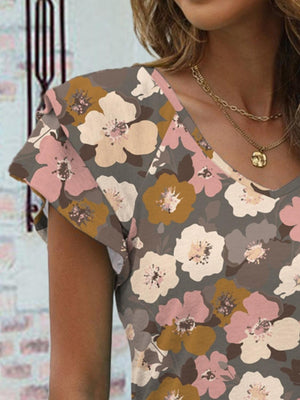 a woman wearing a floral top with a gold necklace