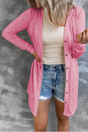 a woman wearing a pink cardigan and denim shorts