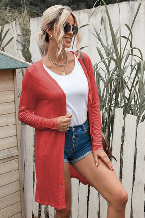 a woman wearing a red cardigan and denim shorts