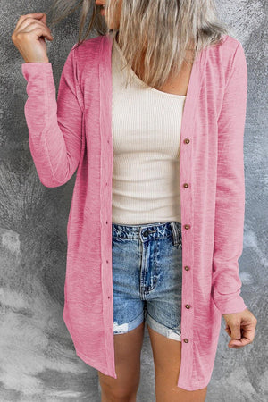 a woman wearing a pink cardigan and denim shorts