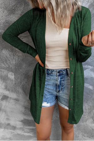 a woman wearing a green cardigan and denim shorts