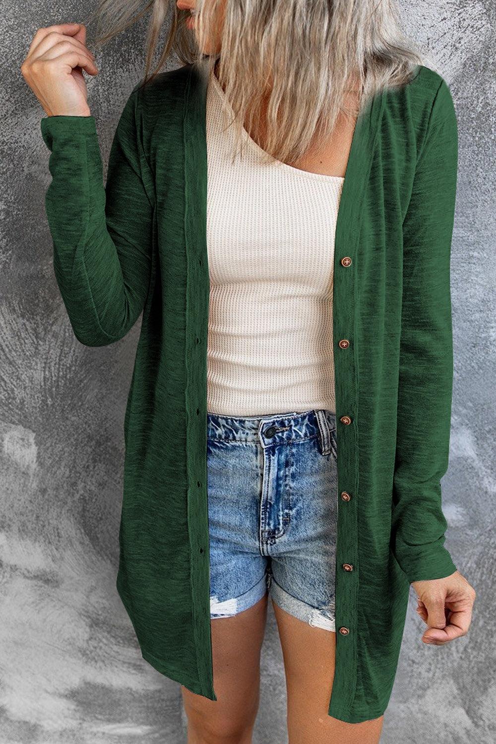 a woman wearing a green cardigan and denim shorts
