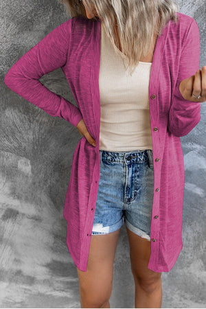 a woman wearing a pink cardigan and denim shorts