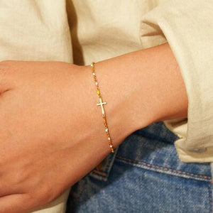 a woman wearing a bracelet with a cross on it