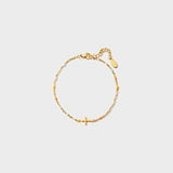 a gold bracelet with a cross charm