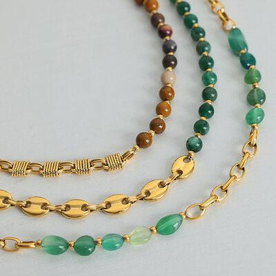 a gold chain with a green bead and a gold plated chain with a