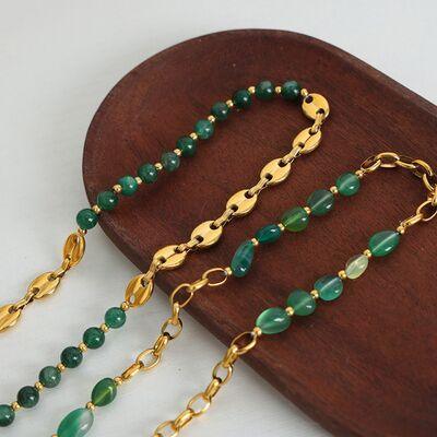 a wooden board with a gold chain and green beads