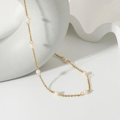 a gold chain bracelet with pearls on a white background