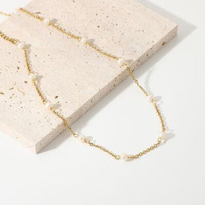 a necklace with pearls on a white surface