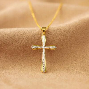 a gold cross necklace on a brown cloth