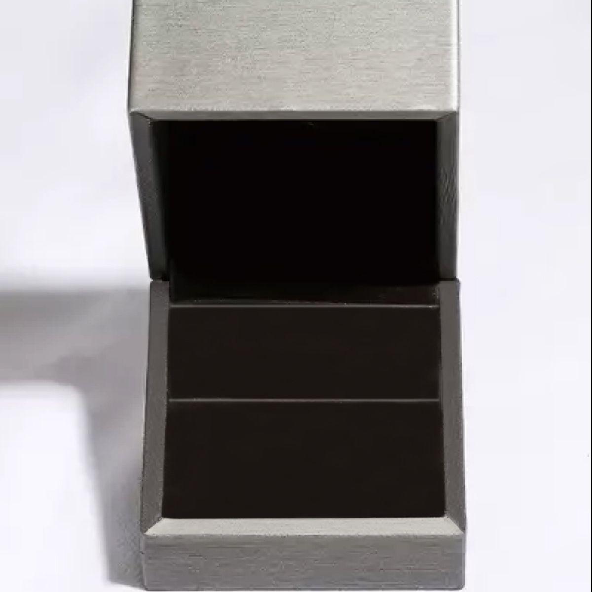 a silver ring with a black box on a white surface