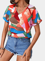 a woman wearing a colorful shirt and denim shorts