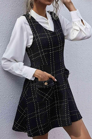 a woman in a black and white dress leaning against a wall