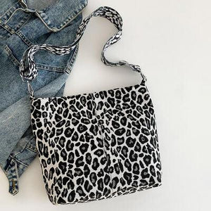 a leopard print purse sitting on top of a pair of jeans