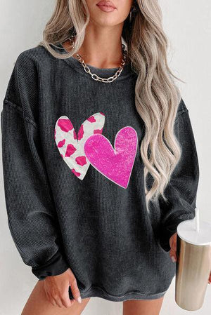 a woman wearing a black sweater with pink hearts on it