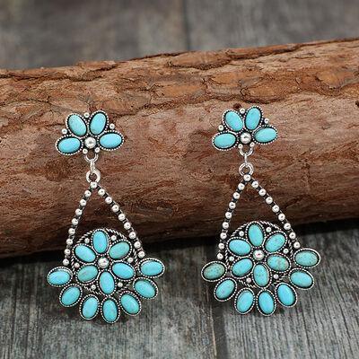 a pair of turquoise earrings sitting on top of a piece of wood