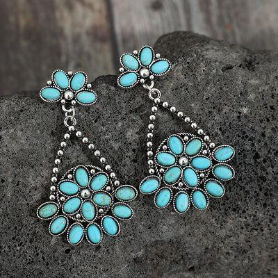 a pair of turquoise earrings sitting on top of a rock