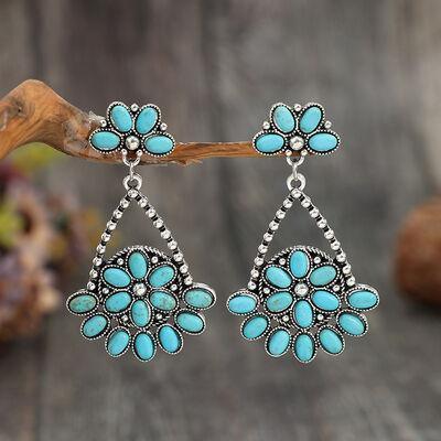a pair of turquoise earrings sitting on top of a wooden table