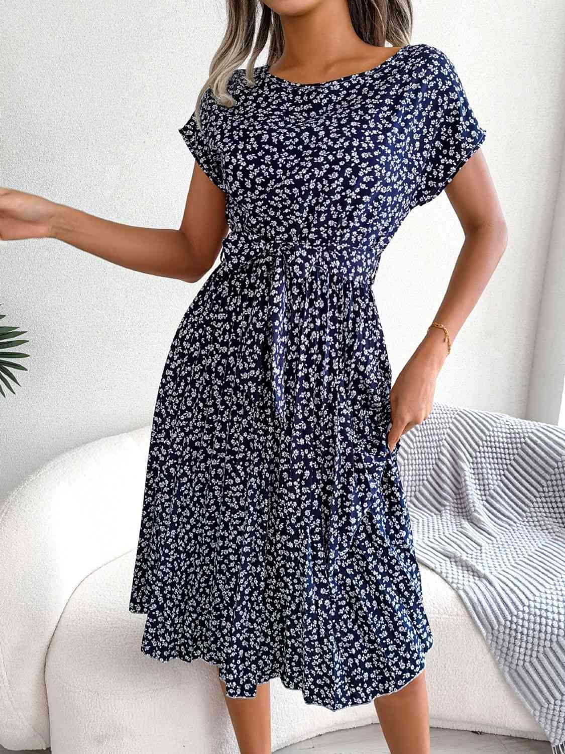 a woman in a blue dress standing in front of a white couch