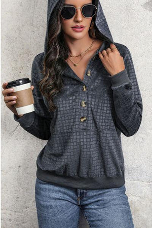 a woman wearing a hoodie and holding a cup of coffee