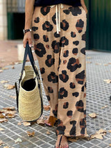 a woman holding a handbag and wearing a leopard print pants