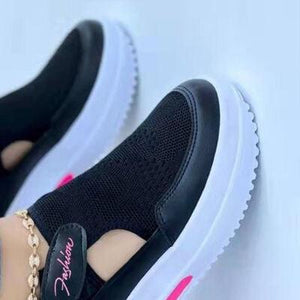 a pair of black sneakers with pink accents