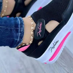 a close up of a person's feet wearing black and pink sneakers