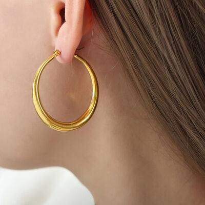 a woman wearing a pair of gold hoop earrings