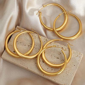 three pairs of gold hoop earrings on a white cloth