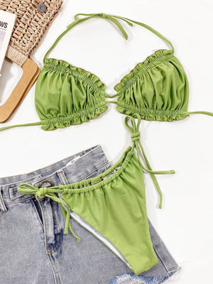 a green bikini top and denim shorts on a white surface