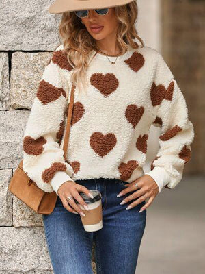 a woman wearing a hat and a sweater with hearts on it