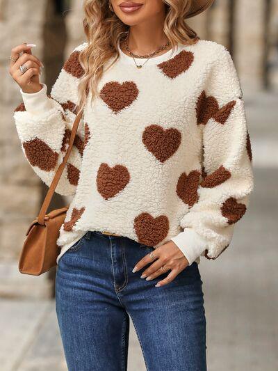 a woman wearing a white sweater with brown hearts on it