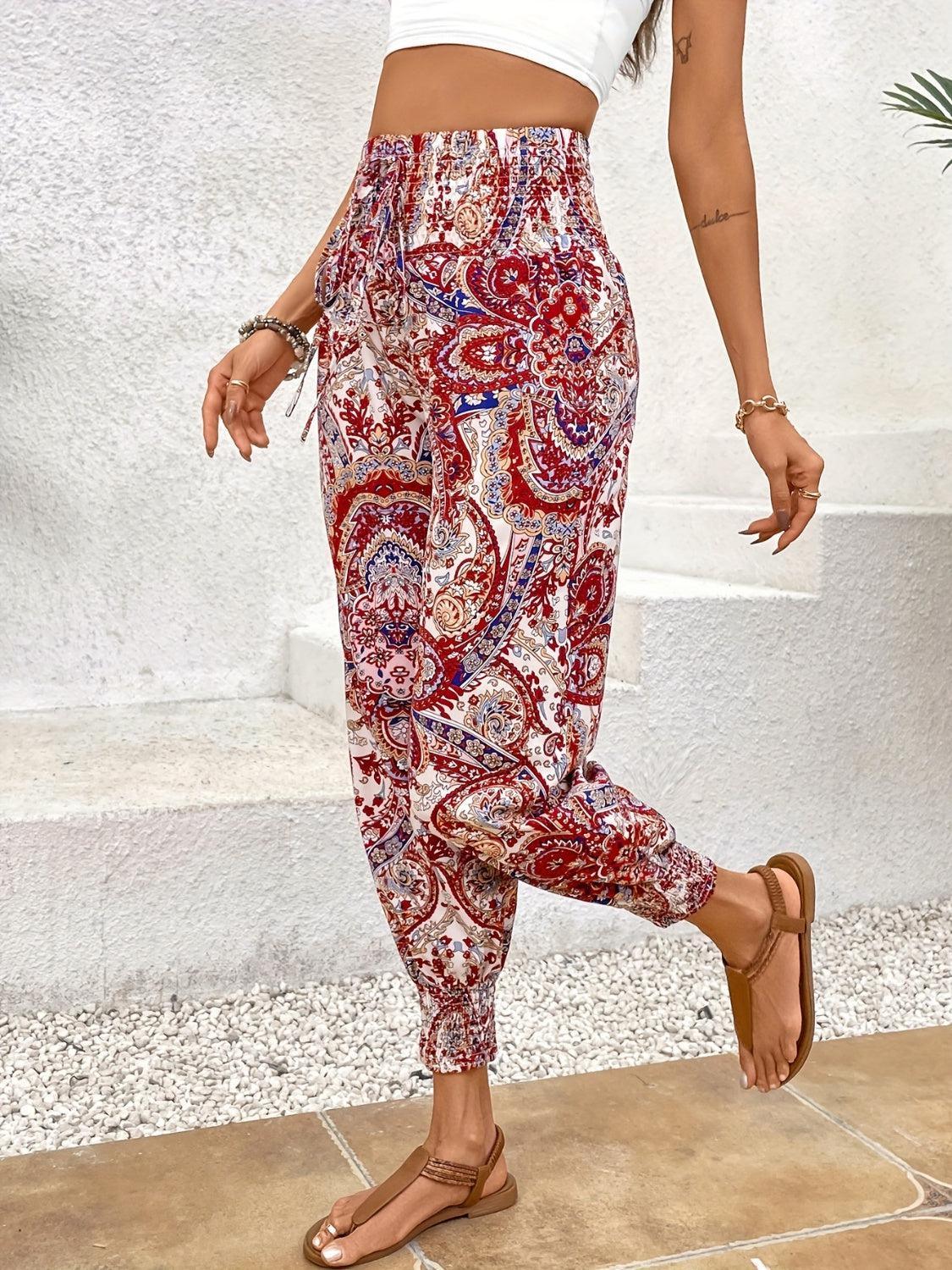 a woman in a white crop top and red paisley print pants