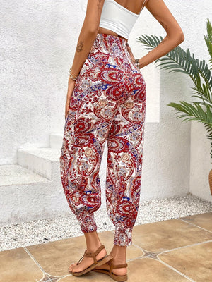 a woman standing on a tile floor wearing a crop top and paisley print pants