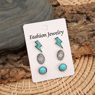 a pair of earrings sitting on top of a piece of wood