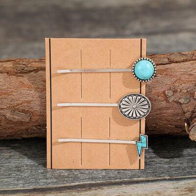 a piece of cardboard with a turquoise brooch and a wooden stick